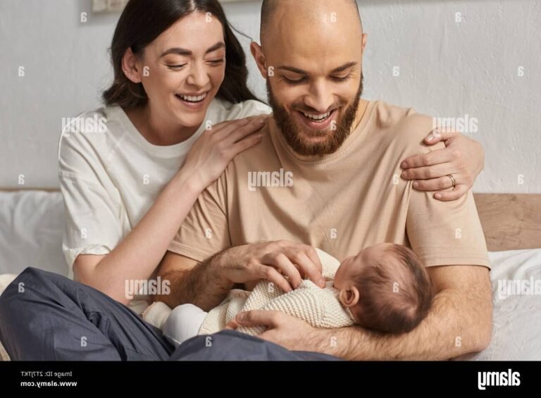 un bebe souriant dans les bras de ses parents