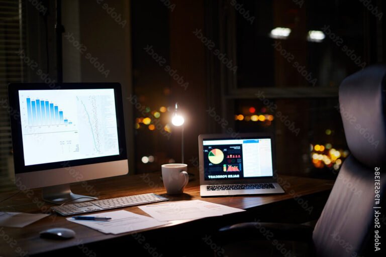 un bureau avec un ordinateur allume la nuit