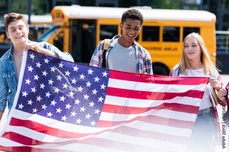 un etudiant souriant devant un drapeau americain